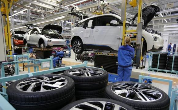 A worker mounts a tyre at the serial production BMW i3 electric car in the BMW factory in Leipzig